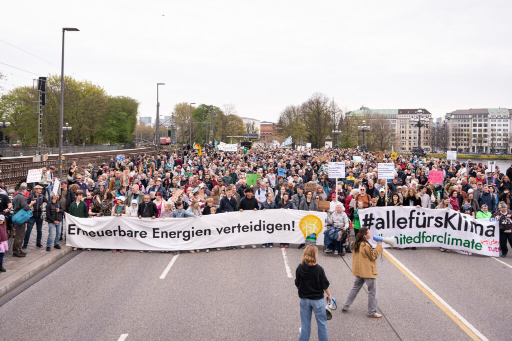 Große Menschenmenge bei Demo mit Bannern "Erneuerbare Energien verteidigen!" und "#allefürklima", in Hamburger Innenstadt, vor der Menge zwei Personen mit Megafonen