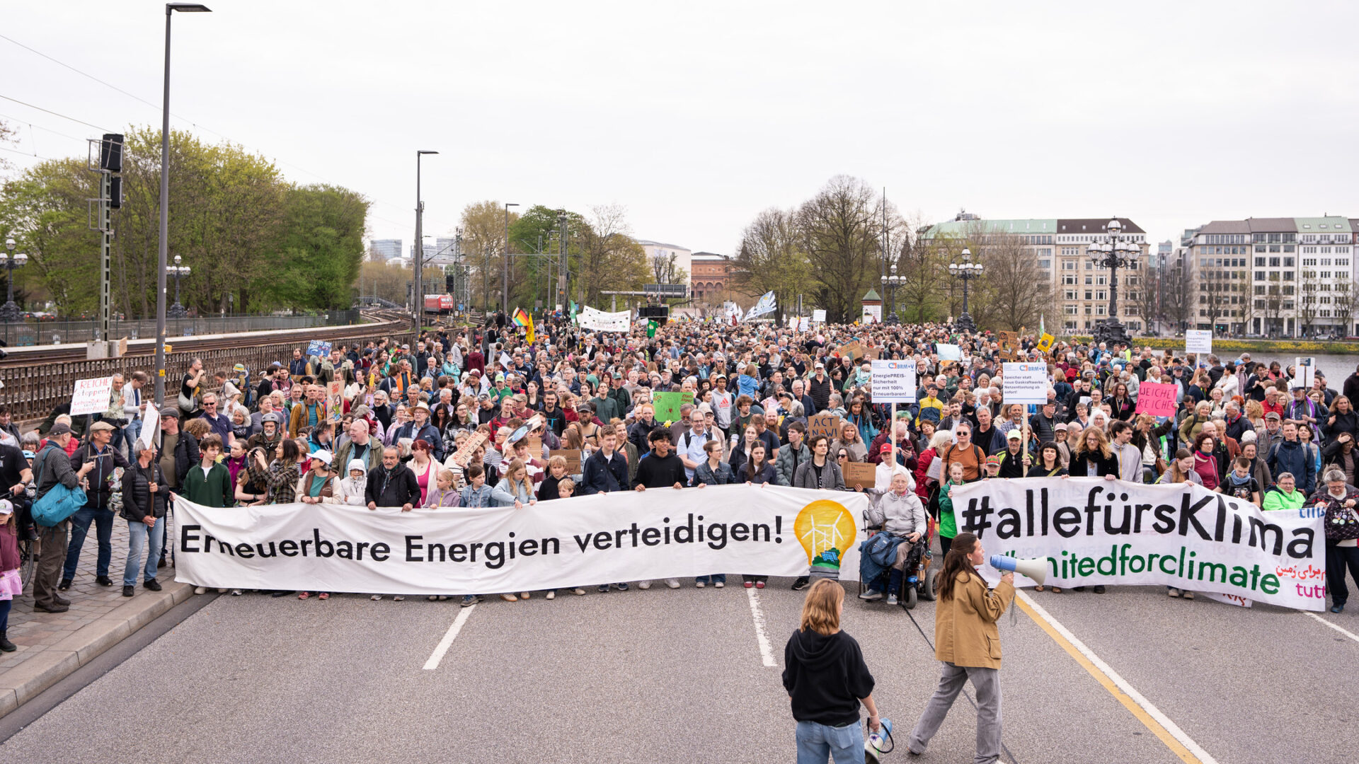 Große Menschenmenge bei Demo mit Bannern "Erneuerbare Energien verteidigen!" und "#allefürklima", in Hamburger Innenstadt, vor der Menge zwei Personen mit Megafonen