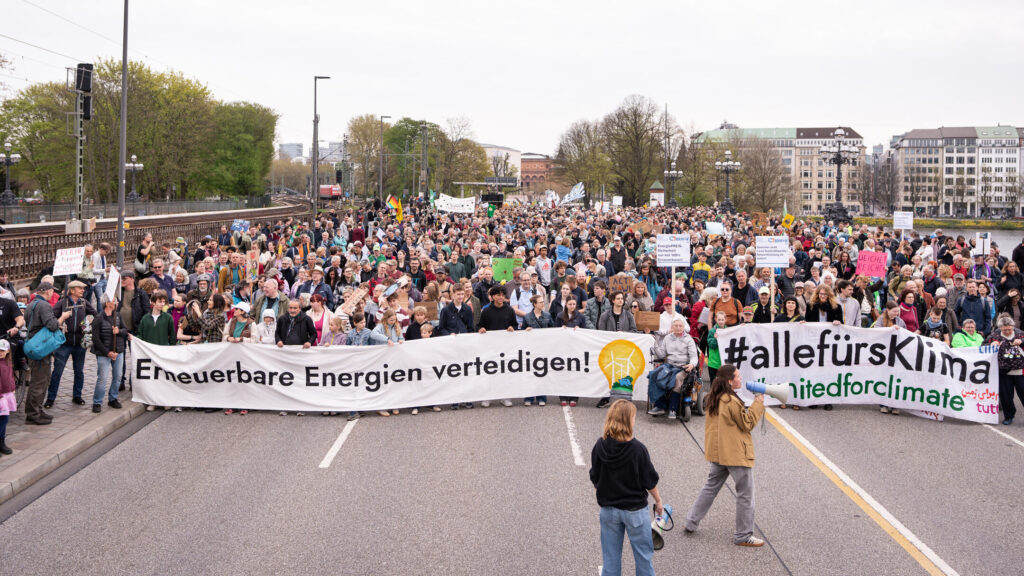 Große Menschenmenge bei Demo mit Bannern "Erneuerbare Energien verteidigen!" und "#allefürklima", in Hamburger Innenstadt, vor der Menge zwei Personen mit Megafonen